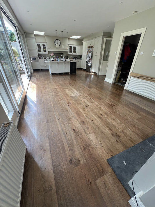 Open-plan kitchen and living room with wide oak plank flooring installed by Kidd Flooring